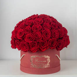 Large dome of red roses arranged in a round red hat box