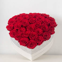 Heart-shaped box filled with tightly packed red roses.