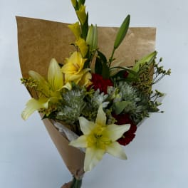 Bouquet of yellow lilies, red carnations, and white chrysanthemums in brown paper