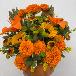 Orange and yellow floral arrangement in a terracotta pot