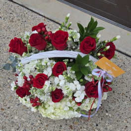 Basket arrangement of red roses and white flowers with ribbon