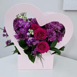 Pink heart-shaped box with purple flowers and magenta roses