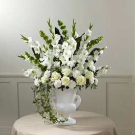 White floral arrangement in a white urn vase