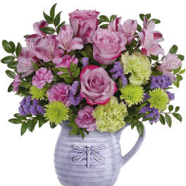 Pink roses and mixed blooms in a lavender pitcher vase
