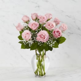 Pink roses arranged in a clear glass vase with baby's breath