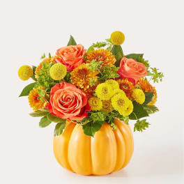 Orange roses and yellow mums arranged in a pumpkin-shaped vase