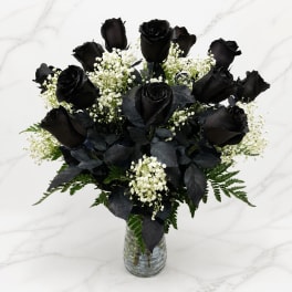 Black roses with white baby's breath in a clear glass vase