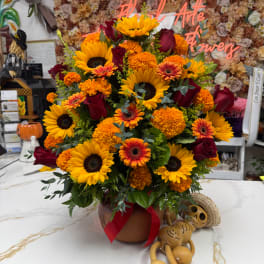 Large bouquet of sunflowers, roses, and orange flowers in a vase