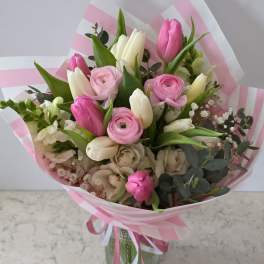 Pink and white mixed bouquet with tulips and ranunculus in striped wrap
