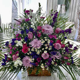 Large mixed bouquet in a woven basket with pink, purple, and white flowers