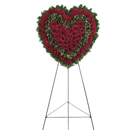 Heart-shaped floral wreath of red roses and carnations on a stand