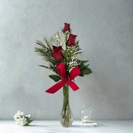 Red roses in a clear glass vase with a red ribbon