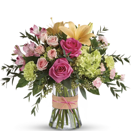 Bouquet of pink roses, lilies, and green hydrangeas in a glass vase