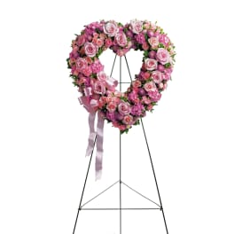 Heart-shaped pink floral wreath on a standing easel with ribbon