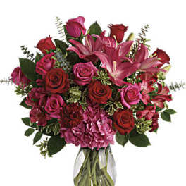 Bouquet of pink lilies and red roses in a clear glass vase
