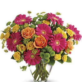 Bouquet of pink gerbera daisies and orange-yellow roses in a clear glass vase