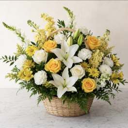 Basket arrangement of white lilies, yellow roses, and white carnations