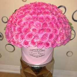 Large pink rose arrangement in a pink hat box on a mirrored stand
