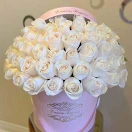 White roses arranged in a pink hatbox with a handle