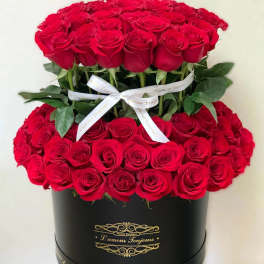 Two tiers of red roses in a black hatbox with a white ribbon
