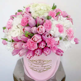 Pink and white tulips and carnations in a pink hatbox