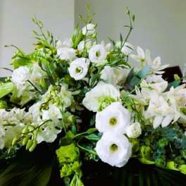 Large white lily and lisianthus spray with green accents displayed in a church setting