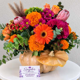 Autumn floral arrangement in a pumpkin container with orange and magenta blooms