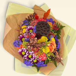 Mixed bouquet with purple, orange, pink, and yellow flowers wrapped in brown paper