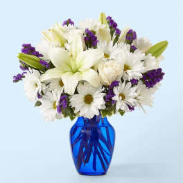 White lilies and daisies in a blue glass vase
