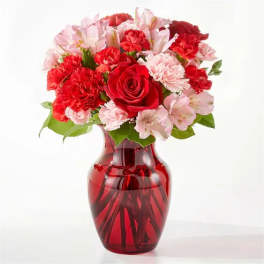 Red and pink flower bouquet in a red glass vase