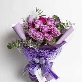 Bouquet of lavender roses wrapped in purple paper with a ribbon