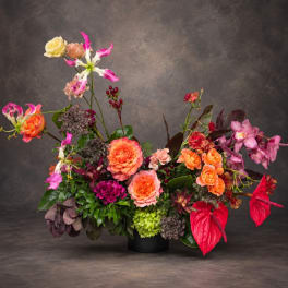 Colorful floral arrangement in a black vase with orange, pink, and purple blooms