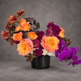 Orange and purple floral arrangement in a black vase
