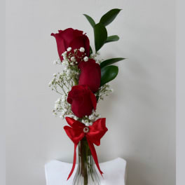 Red roses with baby's breath in a clear vase, tied with a red ribbon
