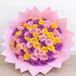 Bouquet of pink, purple, and yellow roses wrapped in pink paper