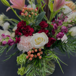Mixed bouquet with pink lilies, white rose, and red carnations in a vase