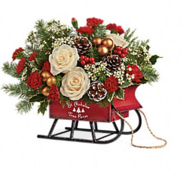 Christmas sleigh arrangement with cream roses, red flowers, and pinecones