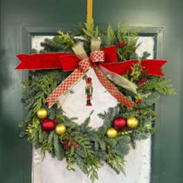 Christmas wreath with red and gold ribbon and ornaments on a door