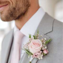 Pink rose boutonniere pinned to a gray suit jacket