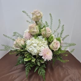 Arrangement of pale roses, white hydrangea, and pink mums in a low design