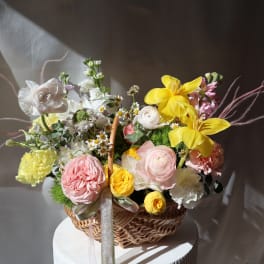 Basket of pastel flowers with yellow blooms and pink roses