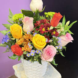 Mixed bouquet of roses and daisies in a white basket