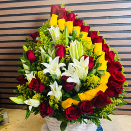 Basket arrangement of red and yellow roses with white lilies