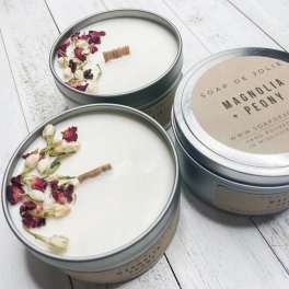 Two floral-scented candles in metal tins with dried petals on top