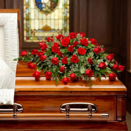 Red rose arrangement on a wooden casket in a funeral setting