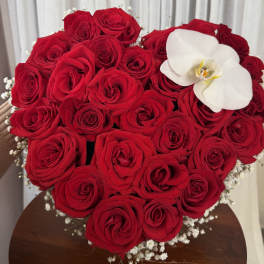 Heart-shaped bouquet of red roses with a white orchid accent