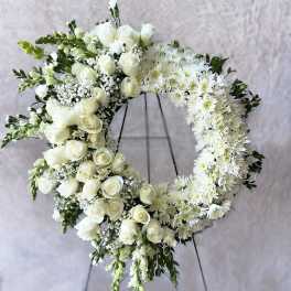Large white rose and mum wreath with cascading blooms on a standing easel