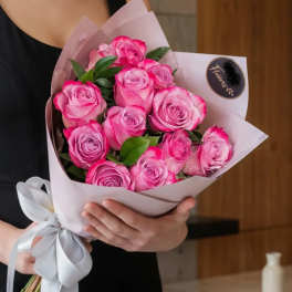 Bouquet of pink roses wrapped in pale paper with a white ribbon