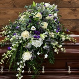 White and purple floral spray arranged on a casket