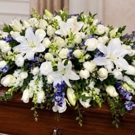 White and blue floral spray on a wooden casket